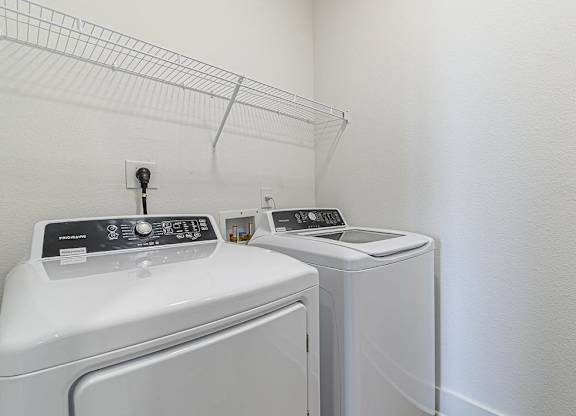 a white laundry room with two washes and a dryer at The Fitzroy San Marcos, San Marcos, TX