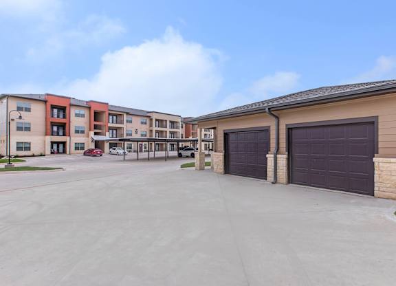 Private garages with apartment buildings in background at Sienna at Westover Hills Apartments, San Antonio, Texas