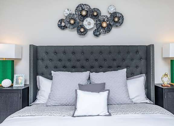 Upholstered tufted bed with decorative wall art at Sienna at Westover Hills Apartments, San Antonio