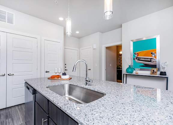 Kitchen island with granite countertop and stainless sink at Sienna at Westover Hills Apartments, San Antonio, TX 78253