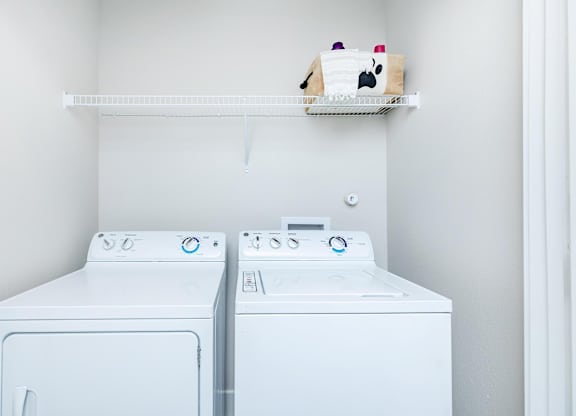 Laundry room with washer dryer and storage shelf at Sienna at Westover Hills Apartments, San Antonio, TX 78253