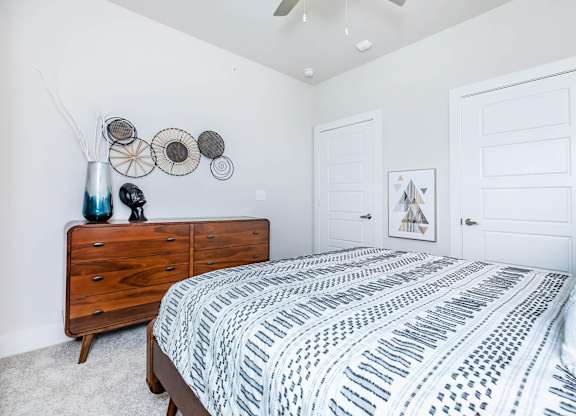 Bedroom with wooden dresser and patterned bedding at Sienna at Westover Hills Apartments, San Antonio, TX 78253