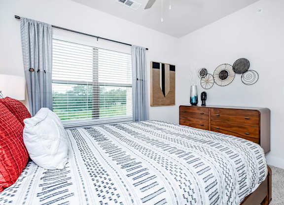 Bedroom with striped bedding and circular wall decor at Sienna at Westover Hills Apartments, San Antonio, 78253