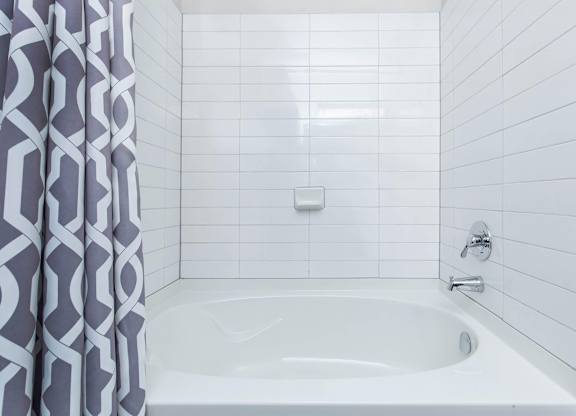 White tiled bathtub with patterned shower curtain at Sienna at Westover Hills Apartments, Texas, 78253