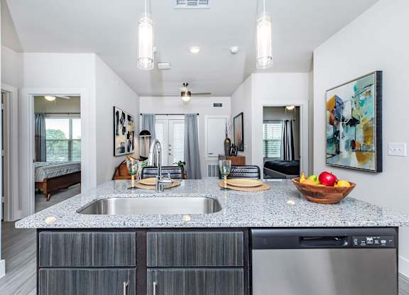 Kitchen island with granite countertop and stainless steel sink at Sienna at Westover Hills Apartments, San Antonio, Texas