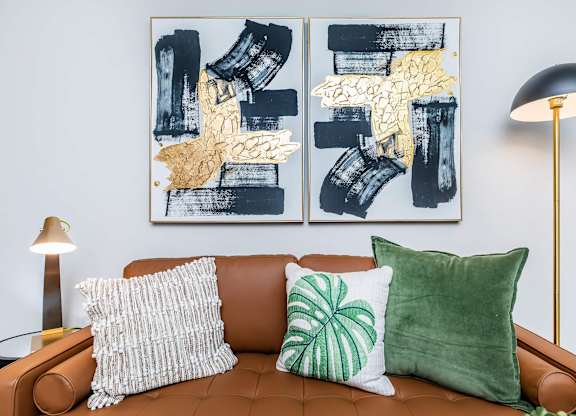 Living room with tan leather sofa and abstract artwork at Sienna at Westover Hills Apartments, San Antonio, TX