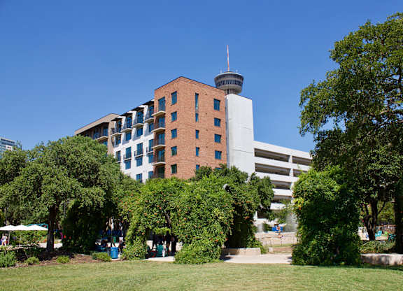 Apartment building exterior with park and trees at THE'68 Apartments, San Antonio