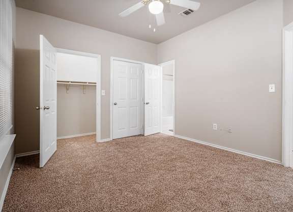 Empty bedroom with beige carpet and closet at Houston Street Townhomes Apartments, San Antonio, TX 78220