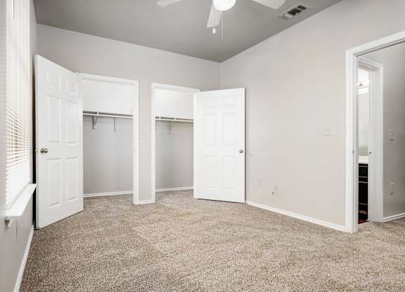 Spacious bedroom with dual closets and carpet at Houston Street Townhomes Apartments, San Antonio, TX