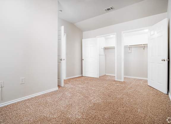 Empty bedroom with carpet and dual closets at Houston Street Townhomes Apartments, San Antonio
