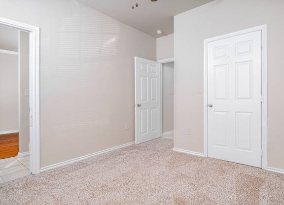 Empty room with carpet and two white doors at Houston Street Townhomes Apartments, San Antonio, 78220