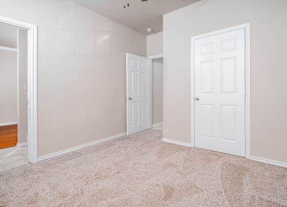 Empty room with beige carpet and white doors at Houston Street Townhomes Apartments, San Antonio, Texas