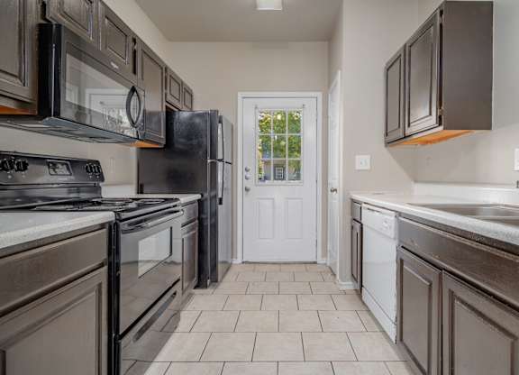 Galley kitchen with white appliances and tile flooring at Houston Street Townhomes Apartments, San Antonio, TX 78220