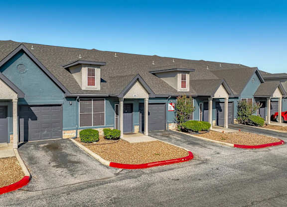Row of townhome garages with blue and tan facades at Houston Street Townhomes Apartments, Texas