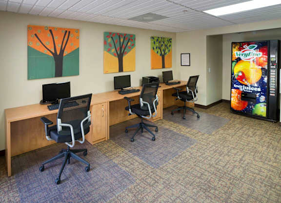 A room with a Verizon billboard and three desks with chairs.