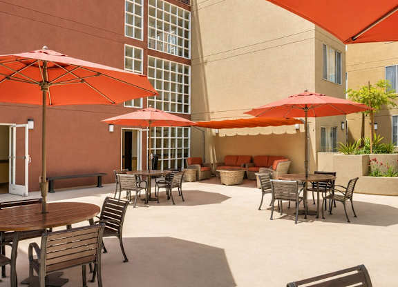 A patio with tables and chairs and umbrellas.