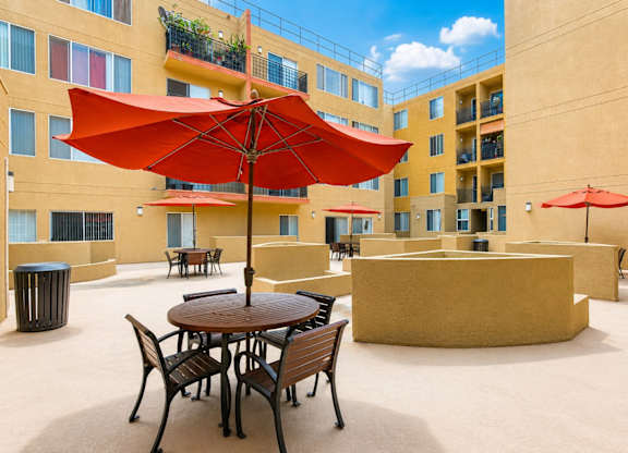 A patio with a table and chairs under a red umbrella.