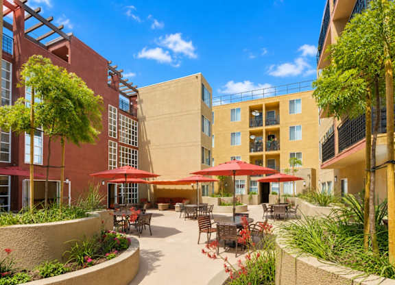 A sunny day at a courtyard with tables and chairs and umbrellas.