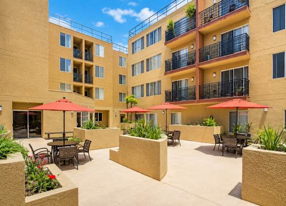 A sunny day at a courtyard with tables and chairs and umbrellas.
