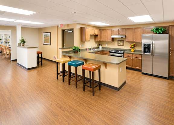 A kitchen with wooden floors and a white island with stools.