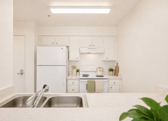 A white kitchen with a sink and a refrigerator.