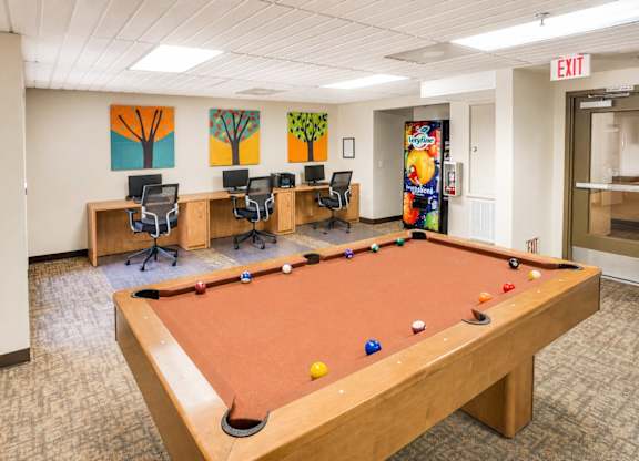 A pool table in a room with a painting on the wall.