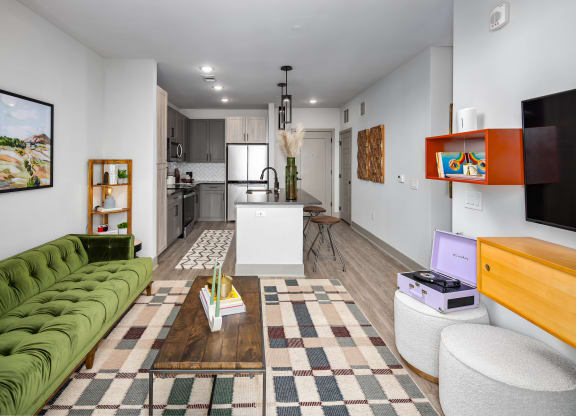 a living room with a green couch and a kitchen in the backgroundat Abberly Foundry Apartment Homes, Nashville, TN, 37206