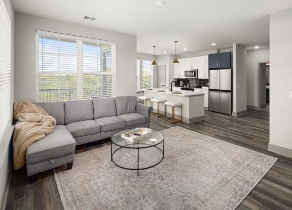 a living room with a couch a table and a kitchen in the background at Abberly Foundry Apartment Homes, Tennessee
