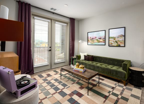 a living room with a green couch and purple curtains at Abberly Foundry Apartment Homes, Nashville