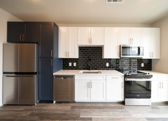 a kitchen with white cabinets and black and white appliances at Abberly Foundry Apartment Homes, Nashville, Tennessee
