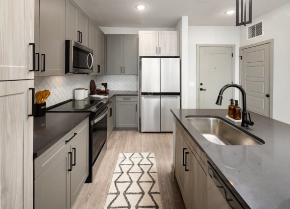 a kitchen with gray cabinets and a black and white rug  at Abberly Foundry Apartment Homes, Nashville, TN, 37203