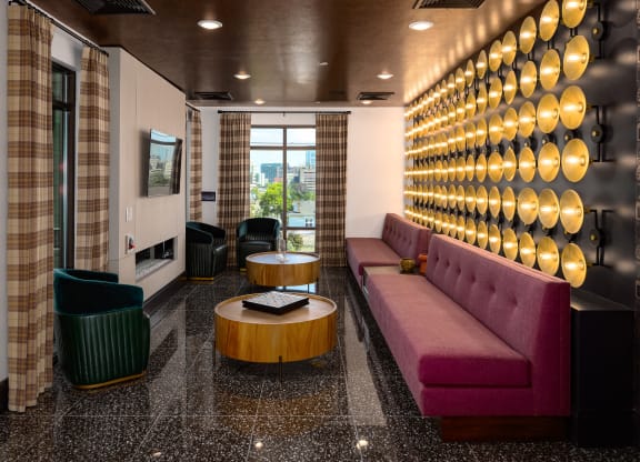 a seating area with a purple couch and a wooden coffee table in front of a wall with at Abberly Foundry Apartment Homes, Nashville, TN, 37206