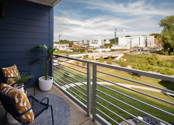 a balcony with a chair and a potted plant and a view of the city  at Abberly Noda Vista Apartment Homes, Charlotte, NC