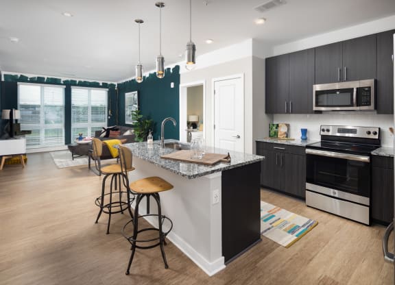 an open concept kitchen and living room with a large island with a granite countertop  at Abberly Noda Vista Apartment Homes, North Carolina