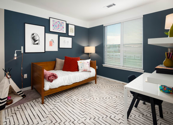 a bedroom with navy blue walls and a white bedspread with red pillows at Abberly Noda Vista Apartment Homes, North Carolina