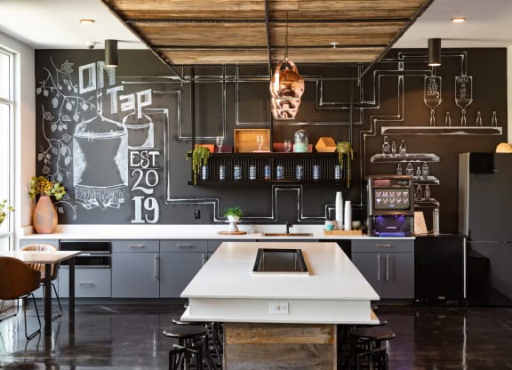 a kitchen with a large white island in front of a chalkboard wall at Abberly Noda Vista Apartment Homes, North Carolina, 28206