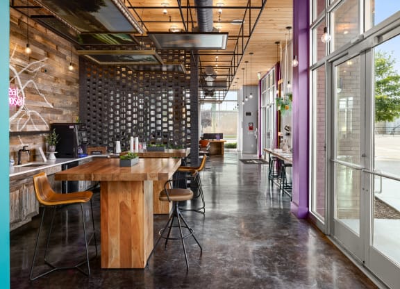 a large wooden table with chairs in a room with glass doors and windows  at Abberly Noda Vista Apartment Homes, North Carolina