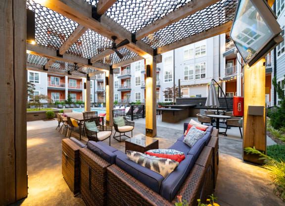 an outdoor patio with wicker furniture and a pergola  at Abberly Noda Vista Apartment Homes, Charlotte