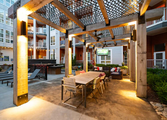 a patio with a wooden table and chairs and a pergola over it  at Abberly Noda Vista Apartment Homes, Charlotte, NC