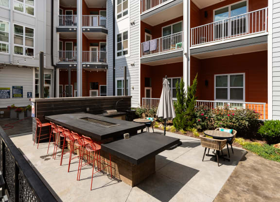 an outdoor patio with a firepit and tables and chairs in front of an apartment building  at Abberly Noda Vista Apartment Homes, Charlotte, NC, 28206