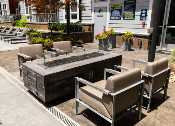 an outdoor seating area with chairs and a firepit in front of a building  at Abberly Noda Vista Apartment Homes, Charlotte