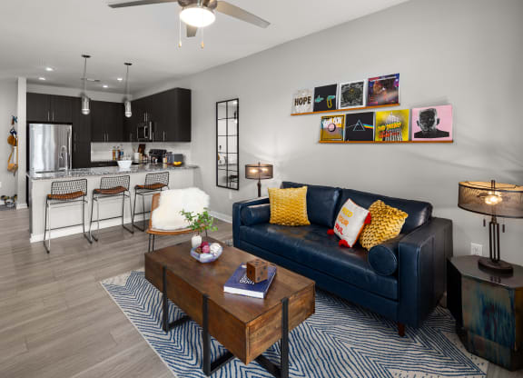 a living room with a black couch and yellow and white pillows  at Abberly Noda Vista Apartment Homes, Charlotte, NC