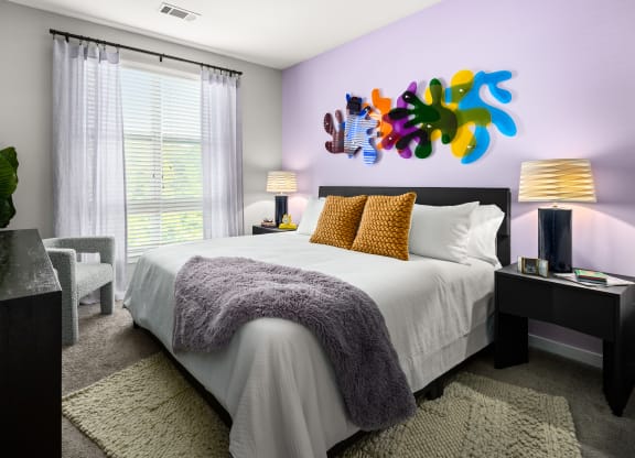 a bedroom with a large bed and a colorful painting on the wall  at Abberly Noda Vista Apartment Homes, Charlotte