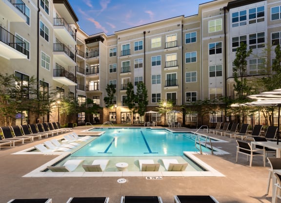 a pool with lounge chairs and umbrellas in front of an apartment building  at Abberly Onyx Apartment Homes, Decatur, 30033