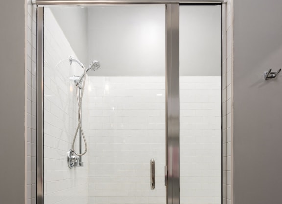 the shower in the master bathroom has a glass door and white tiles at Abberly Onyx Apartment Homes, Georgia, 30033