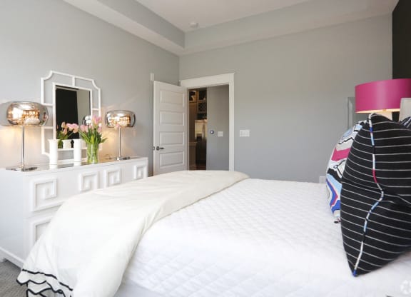 a bedroom with a large white bed and a white dresser with two lamps and  at Abberly Onyx Apartment Homes, Decatur, Georgia