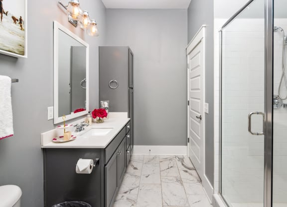 a bathroom with a shower and a sink and a mirror at Abberly Onyx Apartment Homes, Decatur, GA