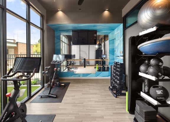 a home gym with a blue accent wall and wood flooring at Abberly Riverwalk Apartment Homes, Nashville, TN