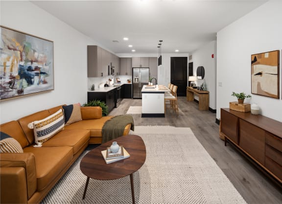 a living room with a brown couch and a coffee table in front of a kitchen with a  at Abberly Riverwalk Apartment Homes, Nashville, Tennessee