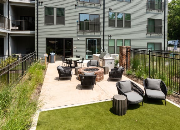 an outdoor patio with a firepit and lounge chairs in front of an apartment building at Abberly Riverwalk Apartment Homes, Nashville, TN